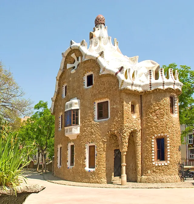 One of the two fairy-tale entrance pavilions of Park Güell, with rough stone walls and a rippling white roof