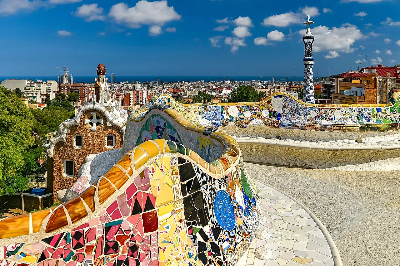 The serpentine bench of the main terrace, a wave of colourful trencadís mosaic, with the two entrance pavilions and the city of Barcelona behind