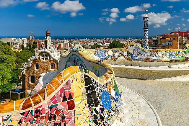 The serpentine bench of the main terrace, a wave of colourful trencadís mosaic, with the two entrance pavilions and the city of Barcelona behind